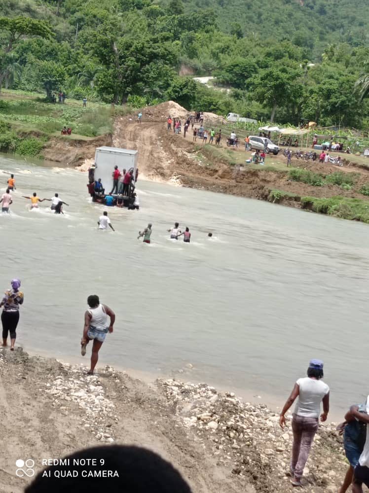 Food, being carried/pushed across the Grand'Anse River on a tractor